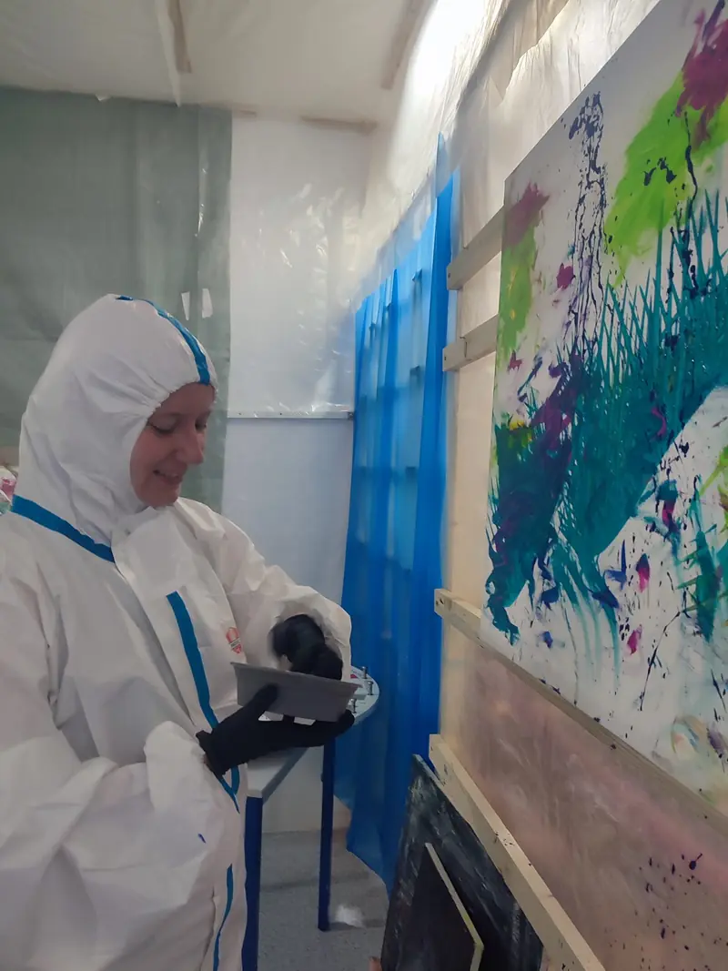 Person gießt Farbe auf eine Leinwand