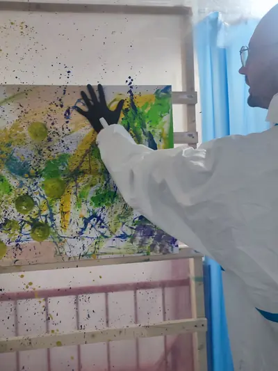 Mit der behandschuhten Hand wird Grün direkt auf die Leinwand gedrückt