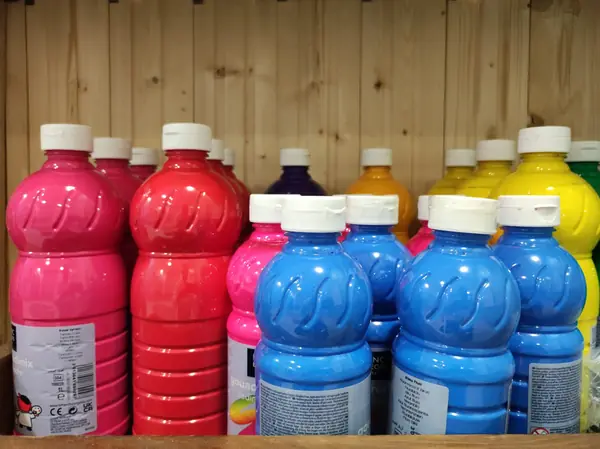 Reihe von Farbflaschen in Pink, Blau und Gelb im Regal