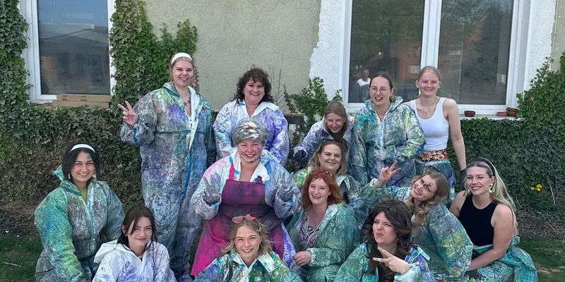 Große Gruppe in bunten Maleranzügen vor dem Atelier am Steinhuder Meer