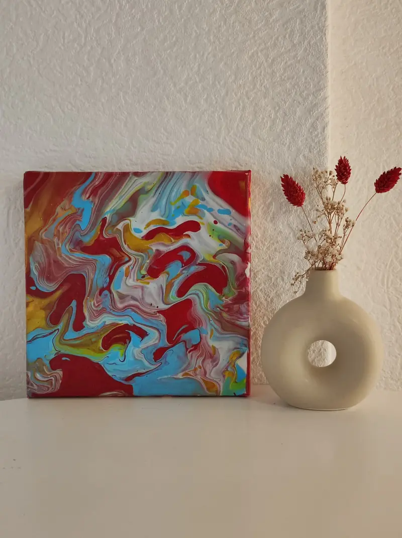 Kleines Pouring-Bild in Rot und Türkis neben einer Vase mit Trockenblumen