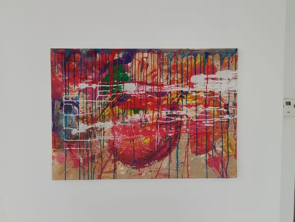 Fertiges Action-Painting-Bild in Rot und Blau hängt an einer weißen Wand